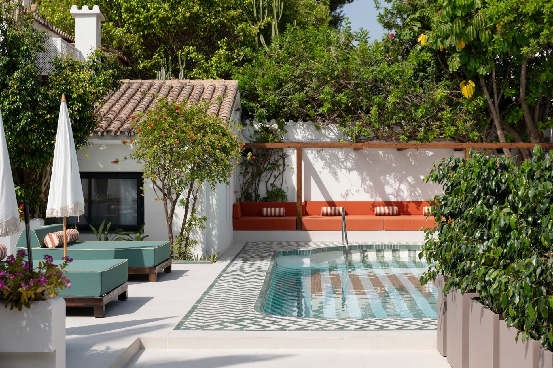 Luxury Mediterranean outdoor terrace with plunge pool, terracotta lounge seating and whitewashed walls surrounded by lush greenery.